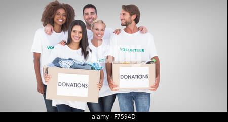 Composite image of happy group of volunteers holding clothes donation boxes Stock Photo