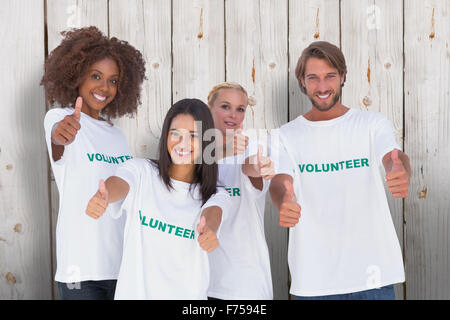 Composite image of happy group of volunteers giving thumbs up Stock Photo