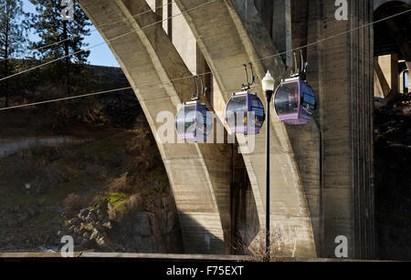 Skyride gondolas cross Spokane River directly below the waterfall then pass under Monroe Bridge from Huntington Park; Spokane. Stock Photo