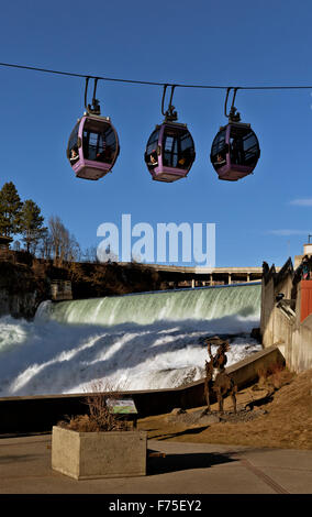 Skyride gondolas cross Spokane River directly below the waterfall then pass under Monroe Bridge from Huntington Park; Spokane. Stock Photo