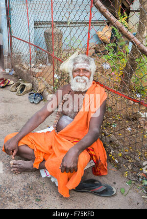 Old man devotee dressed wearing saffron robe sitting outside the Kapaleeswarar Temple, a Hindu temple of Shiva, Mylapore, Chennai, Tamil Nadu, India Stock Photo