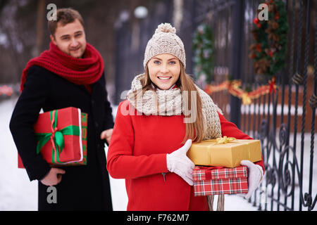 Smiling woman standing with gift boxes with man behind her Stock Photo