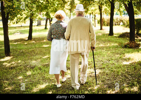 Happy seniors taking a walk in the park on sunny day