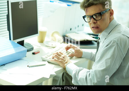 Businessman with bruised face looking at camera while typing Stock Photo