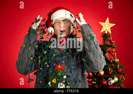 Surprised man with garland all over him looking at camera Stock Photo