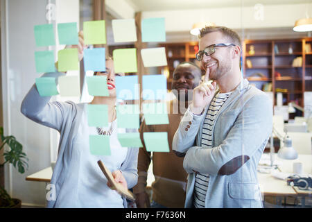 Confident managers reading working points on reminders in office Stock Photo