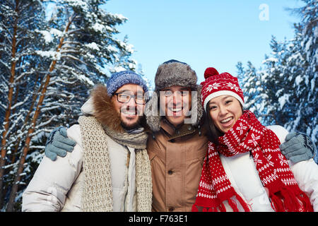 Happy friends in winterwear looking at camera outdoors Stock Photo