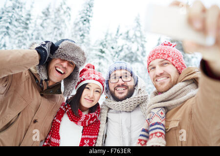 Happy friends in winterwear making selfie in park Stock Photo