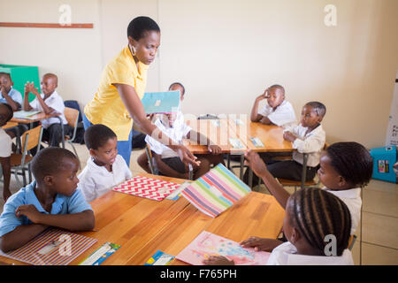 SOUTH AFRICA- Teacher handing out folders in classroom. Stock Photo