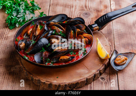 oyster mussels in red sauce in a frying pan Stock Photo