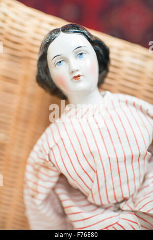 Pensive porcelain toy doll. Old fashioned retro design. Stock Photo