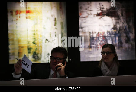 Employees at the Van Ham auction house accept bids per phone in front of paintings by the artist Gerhard Richter in Cologne, Germany, 26 November 2015. Pieces by Gerhard Richter are being auctioned in support of the Duesseldorf-based street magazine 'fiftyfifty' at the Van Ham auction house. Photo: OLIVER BERG/dpa