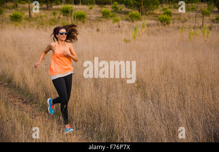 Shot of an attractive woman running outdoor on a meadow Stock Photo