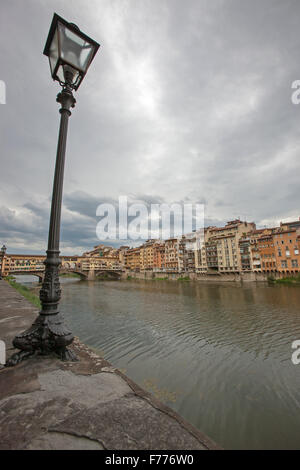 Street lamp on bank of river Arno with Ponte Vecchio and Florence in distance Stock Photo