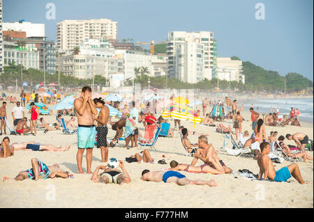 RIO DE JANEIRO, BRAZIL - OCTOBER 21, 2015: Sunbathers relax on the shore of Ipanema Beach, one of the city's popular beaches. Stock Photo