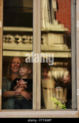 New York, USA. 25th November, 2015. Macy's Thanksgiving day parade. A mom and her children take in the Macy’s Thanksgiving Day Parade from inside on Thursday, Nov. 26, 2015. Credit:  Shoun Hill/Alamy Live News Stock Photo