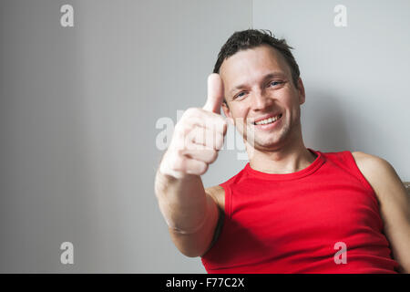 Positive young smiling Caucasian man shows thumbs up gesture, studio portrait Stock Photo