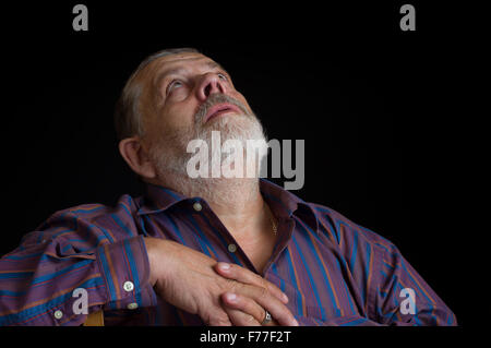 Nice portrait of a bearded senior man in striped shirt looking up Stock Photo