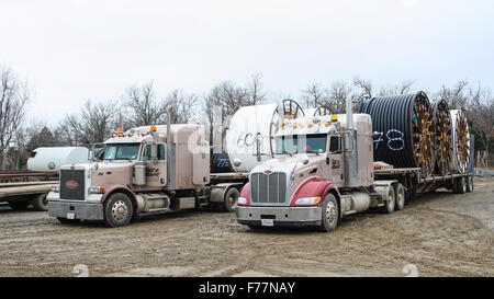 Two American Peterbilt 379 semi trucks hauling reels of HDPE plastic pipe on a flatbed trailer for the oil industry and fracking sites in the USA Stock Photo
