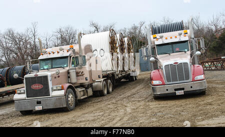 Two American Peterbilt 379 semi trucks hauling reels of HDPE plastic pipe on a flatbed trailer for the oil industry and fracking sites in the USA Stock Photo