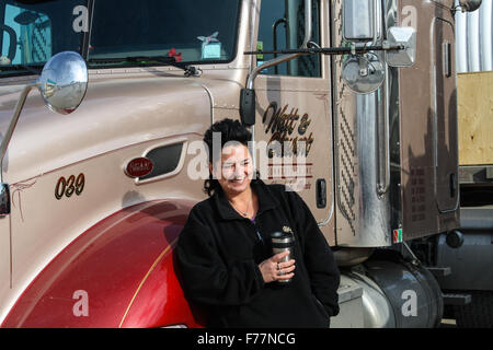 Female, Dutch truck driver poses beside her 'Watt and Stewart' Canadian company Peterbilt truck in Dalhart, Texas, USA with a coffee. Stock Photo