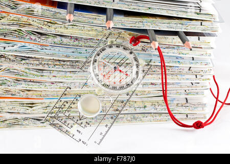 Stack of ordnance Survey maps along with a compass and 4 pencils Stock Photo