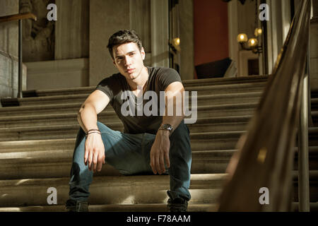 Young Handsome Man Stitting on Stairs Inside an Architectural Elegant Old Building While Looking at Camera Stock Photo