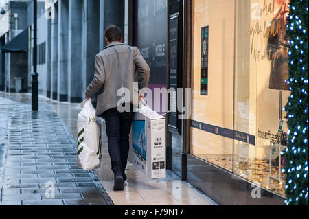 - London, UK.  27 November 2015.  A man walks by clutching a new television and more in Oxford Street, central London, on what is known as 'Black Friday', a day when retailers cut prices in the run up to Christmas.  Retailers had expected large early morning crowds, but they failed to materialise.   Credit:  Stephen Chung / Alamy Live News Stock Photo