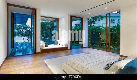 Interior of a house in Cove Way, Sentosa, Singapore designed by Robert Greg Shand Architects. Recessed day bed in window overlooking terrace. Stock Photo