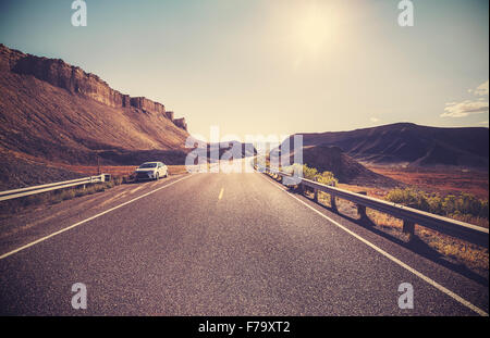 Retro toned desert highway against sun, travel concept. Stock Photo