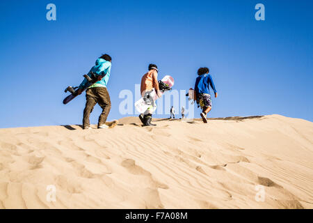 Sandboarders walking on Cerro Dragon, a sand dune located next to the city of Iquique, in Atacama Desert. Stock Photo