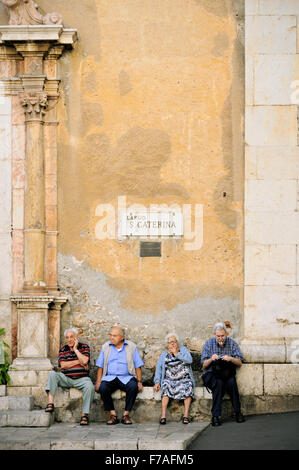 Four mature people sitting outside Santa Caterina church in Taormina, Sicily, Italy Stock Photo