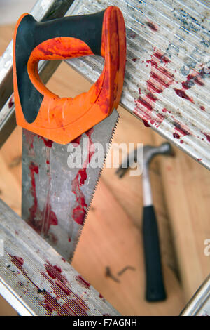 A hammer and carpenters saw with blood after a diy accident UK Stock Photo