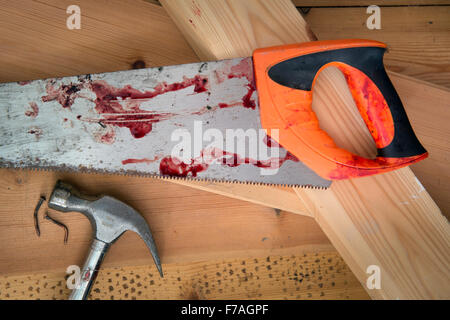 A hammer and carpenters saw with blood after a diy accident UK Stock Photo