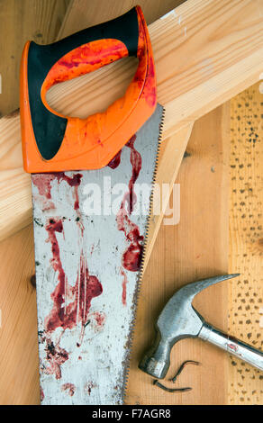 A hammer and carpenters saw with blood after a diy accident UK Stock Photo