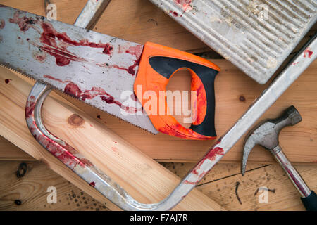 A hammer and carpenters saw with blood after a diy accident UK Stock Photo