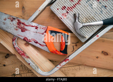 A hammer and carpenters saw with blood after a diy accident UK Stock Photo