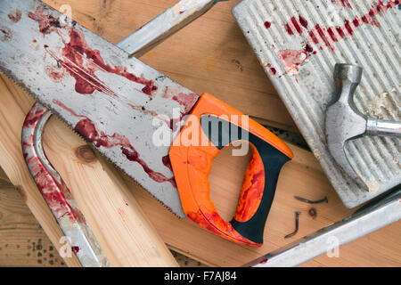 A hammer and carpenters saw with blood after a diy accident UK Stock Photo