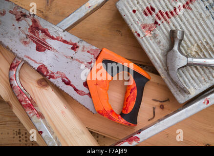 A hammer and carpenters saw with blood after a diy accident UK Stock Photo