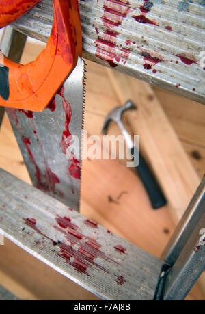 A hammer and carpenters saw with blood after a diy accident UK Stock Photo