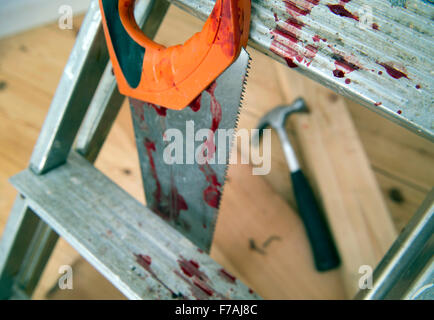 A hammer and carpenters saw with blood after a diy accident UK Stock Photo