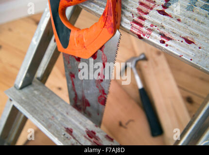 A hammer and carpenters saw with blood after a diy accident UK Stock Photo