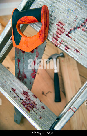 A hammer and carpenters saw with blood after a diy accident UK Stock Photo