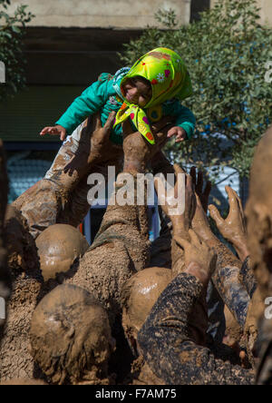 Iranian Shiite Muslim Men Covered In Mud Holding An Ill Girl During Ashura Day, Kurdistan Province, Bijar, Iran Stock Photo