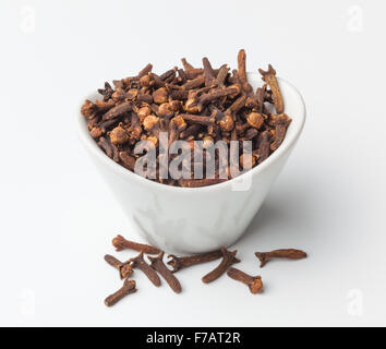 Dried cloves in a bowl, isolated on white background. Stock Photo