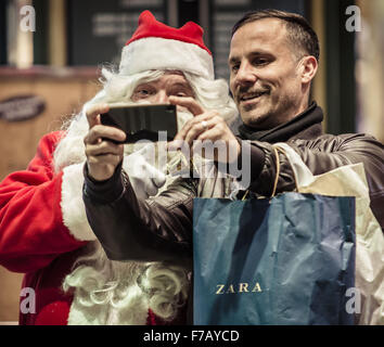 Barcelona, Catalonia, Spain. 27th Nov, 2015. A shopper takes a selfie with a Santa Claus on his first working day in front of a big store in Barcelona - The festive season 2015 gets underway in Barcelona as Christmas lights and trees are switched on in the streets © Matthias Oesterle/ZUMA Wire/Alamy Live News Stock Photo