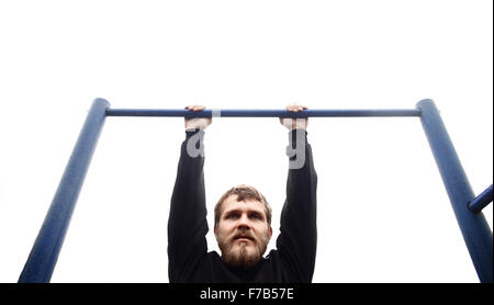 young man doing pull ups on horizontal bar outdoors Stock Photo