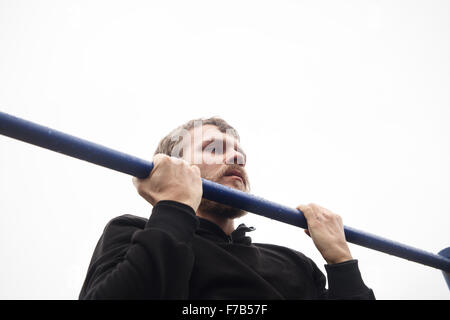 young man doing pull ups on horizontal bar outdoors Stock Photo