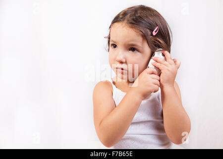 Little girl with ear talking electronic thermometer taking herself the temperature. Isolated over white background Stock Photo