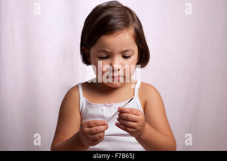 little girl looking to a clinical mercury-in-glass thermometer Stock Photo